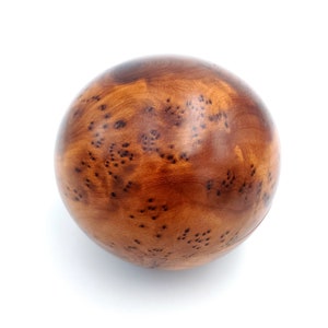 May include: A smooth, round wooden ball with a brown and dark brown wood grain pattern. The ball has a natural, rustic look.