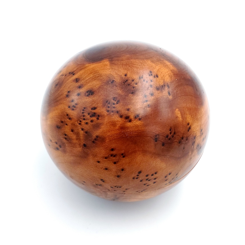 May include: A smooth, round wooden ball with a brown and dark brown wood grain pattern. The ball has a natural, rustic look.