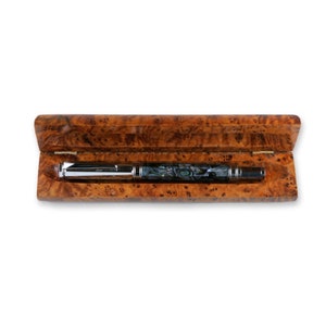 May include: A silver and blue pen with a marbled design is in a wooden box with a burl wood finish.