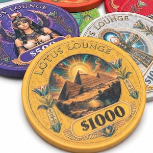 Könnte beinhalten: Eine Sammlung runder Pokerchips mit ägyptisch inspirierten Illustrationen und dem Schriftzug Lotus Lounge. Die Chips sind in hohen Stapeln und verstreuten Haufen angeordnet und zeigen verschiedene Farben wie Türkis, Rot, Pink, Gelb und Grün.