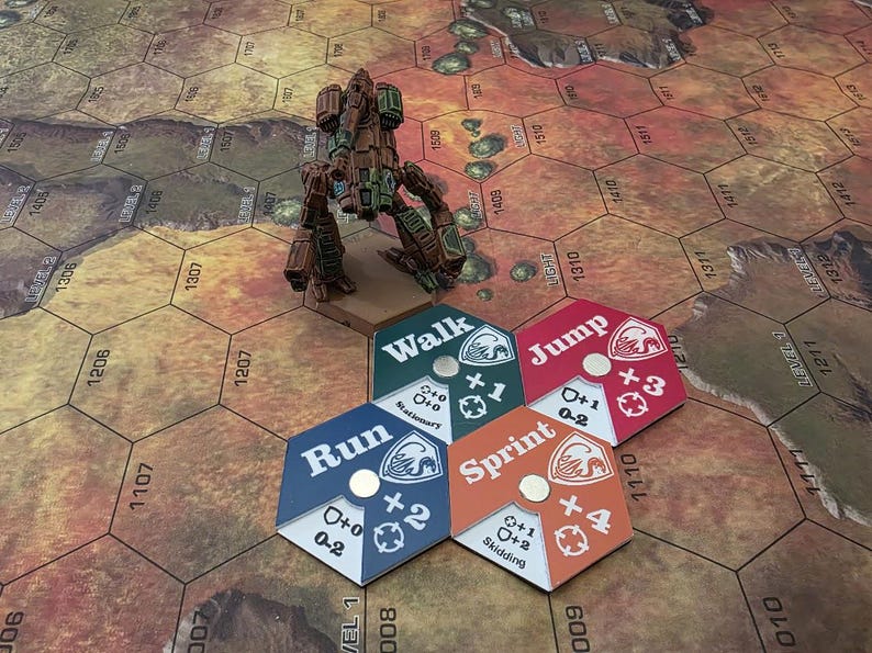 Pode incluir: Um close-up de um tabuleiro de jogo com um rob&ocirc; em miniatura e cinco pe&ccedil;as hexagonais. As pe&ccedil;as s&atilde;o codificadas por cores e t&ecirc;m diferentes op&ccedil;&otilde;es de movimento: Andar, Correr, Sprintar, Saltar. As pe&ccedil;as s&atilde;o etiquetadas com o n&uacute;mero de espa&ccedil;os que o jogador pode mover.