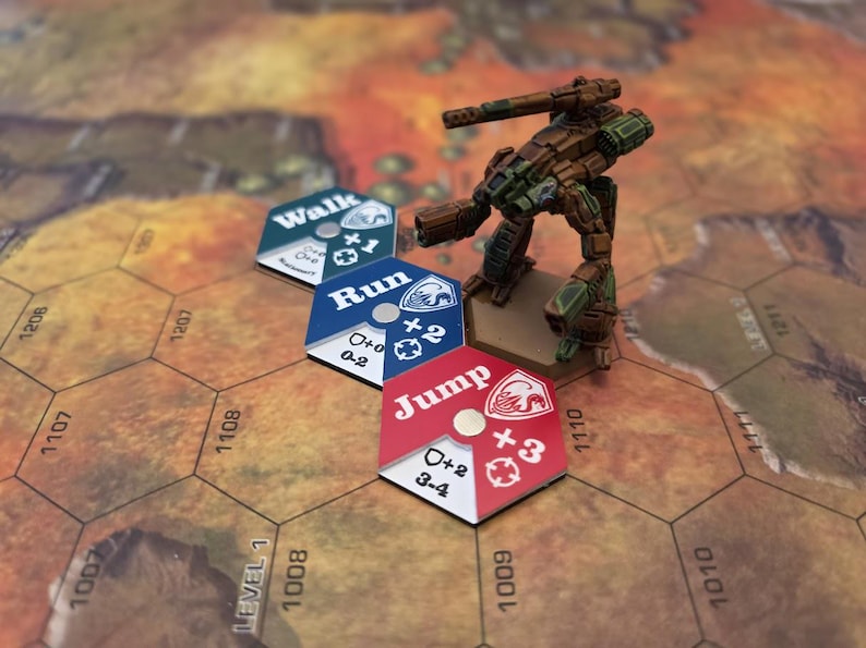 Puede incluir: Una figura de juego de guerra en miniatura de un mech, pintada en colores de camuflaje, se encuentra en un tablero de juego hexagonal. La figura est&aacute; junto a tres fichas de juego hexagonales, etiquetadas como "Walk", "Run" y "Jump".