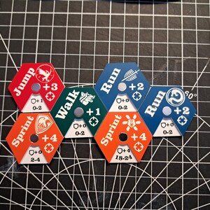 Pode incluir: Seis pe&ccedil;as de jogo hexagonais com diferentes op&ccedil;&otilde;es de movimento: Salto, Sprint, Caminhada, Corrida, Sprint, Corrida. Cada pe&ccedil;a tem um &iacute;cone e valores num&eacute;ricos diferentes. As pe&ccedil;as est&atilde;o dispostas em c&iacute;rculo.
