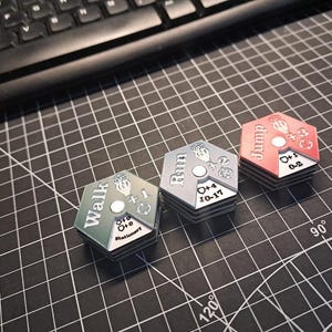 Pode incluir: Tr&ecirc;s pe&ccedil;as de jogo hexagonais com diferentes op&ccedil;&otilde;es de movimento: "Caminhar", "Correr" e "Saltar". Cada pe&ccedil;a tem uma cor diferente: verde, azul e vermelho. As pe&ccedil;as t&ecirc;m n&uacute;meros e s&iacute;mbolos.