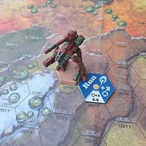 Puede incluir: Una figura de robot en miniatura de color marr&oacute;n y verde con una pistola, de pie en un tablero de juego hexagonal con una ficha azul y blanca que dice "Run" y tiene un s&iacute;mbolo de m&aacute;s dos y un s&iacute;mbolo de m&aacute;s dos con 5-6 escrito debajo. El tablero tiene n&uacute;meros y texto que dice "Nivel 1" y "Nivel 2".