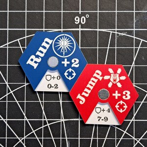 Puede incluir: Dos piezas de juego hexagonales, una azul con la palabra "Run" y la otra roja con la palabra "Jump". Ambas piezas tienen un escudo blanco con un rango de n&uacute;meros y un signo m&aacute;s con un n&uacute;mero.
