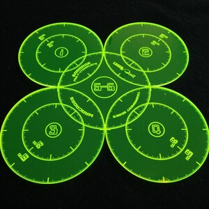May include: Five green plastic circular rulers with different markings and numbers. The rulers are arranged in a circular pattern with the numbers 1, 2, 3, 4, 5-6, and Q visible.