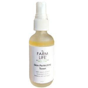 May include: A clear glass bottle with a white spray top, labeled "The FARM LIFE" and "Skin Perfecting Toner" with the text "with neem oil and essential oils to balance all skin types" and "2 oz".