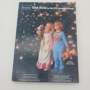 May include: The cover of the 1976 Sears Wish Book features two children in pajamas holding stuffed animals. The catalog cover has the text "Sears Wish Book for the 1976 Christmas Season". The background is a dark blue with sparkling stars.