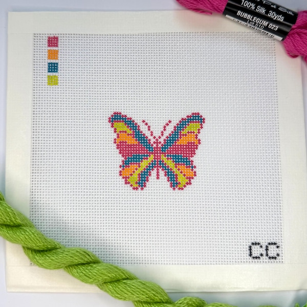 Può includere: Una tela per punto croce con un vivace disegno a farfalla, cucito con fili rosa, arancioni, blu e gialli. Una piccola tavolozza di colori è nell'angolo in alto a sinistra. Fili rosa e verdi sono anche nell'immagine.