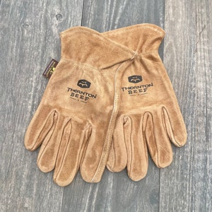 May include: A pair of brown leather work gloves with the text "Thornton Beef" on each glove.