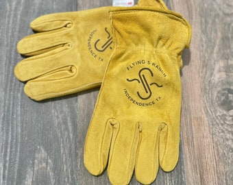 May include: A pair of yellow leather work gloves with the logo "Flying S Ranch Independence TX" printed on them.