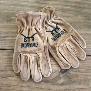 May include: A pair of brown leather work gloves with black stitching and the text "BTR BACKYARD RANCH" on each glove.