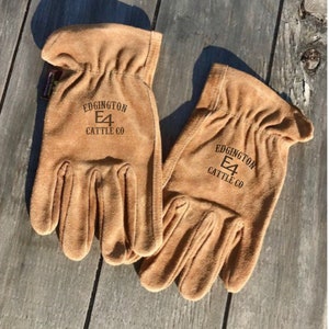 May include: A pair of brown leather work gloves with the text "Edgington E4 Cattle Co" on the back of each glove.