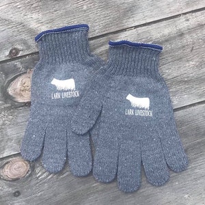 May include: A pair of gray work gloves with a white cow silhouette and the text "Lark Livestock" on each glove.