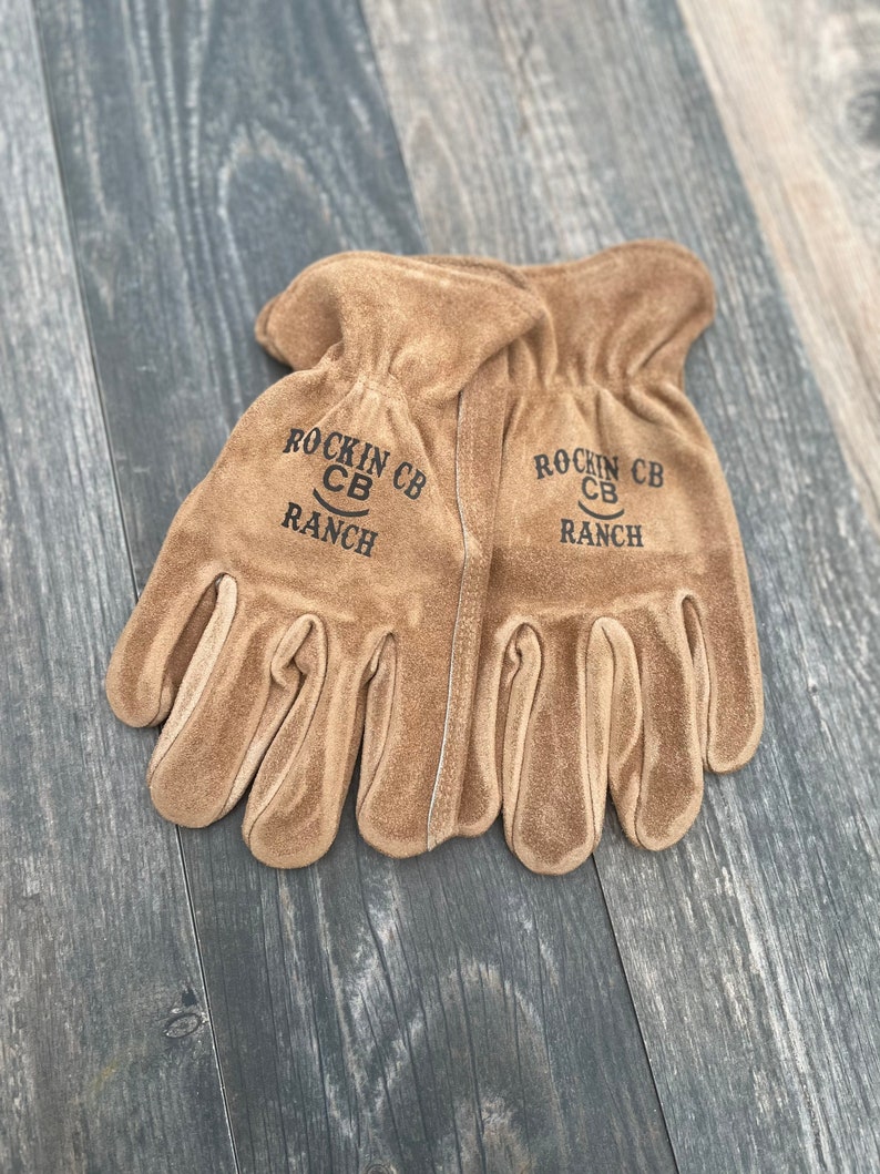 May include: A pair of brown leather work gloves with the text "Rockin' CB Ranch" on each glove.