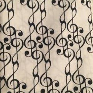 May include: White fabric with a black treble clef pattern.