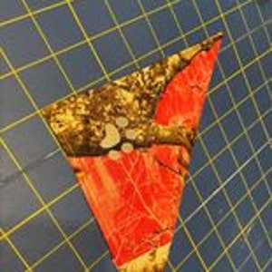 May include: A pink, brown, and white camouflage bandana with a triangular shape.