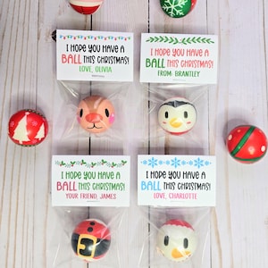 May include: A collection of Christmas-themed decorative balls, each with a unique character design, including Santa, a reindeer, and a penguin. Each ball is packaged with a small card that reads "I hope you have a ball this Christmas!" and a name.
