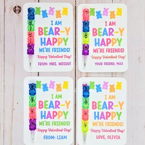 May include: Four Valentine's Day cards with colorful text and bear-shaped pen toppers. Each card reads "I AM BEAR-Y HAPPY WE'RE FRIENDS! Happy Valentine's Day!" with a different name at the bottom. The pens have blue, green, pink, and purple bears.