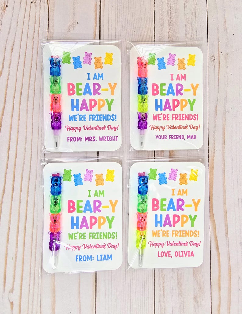 May include: Four Valentine's Day cards with colorful gummy bear pens. Each card reads "I AM BEAR-Y HAPPY WE'RE FRIENDS! Happy Valentine's Day!" with different names. The pens are made of stacked gummy bear shapes in various colors.
