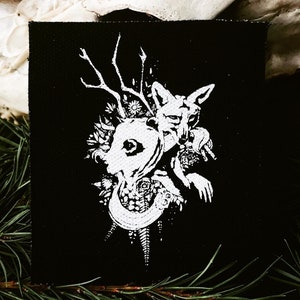 May include: A black canvas art piece featuring a white illustration of a fox, a human profile, antlers, and floral elements. The artwork has a gothic or mystical theme, with detailed linework and a striking contrast.