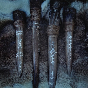 May include: Four wooden daggers with white painted designs. The daggers are wrapped in brown twine and have a pointed tip.