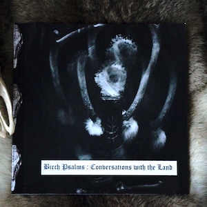 May include: Black and white photo of a deer antler with the text "Birch Psalms: Conversations with the Land" printed below.