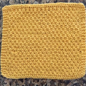 May include: A yellow knitted dishcloth with a textured pattern.