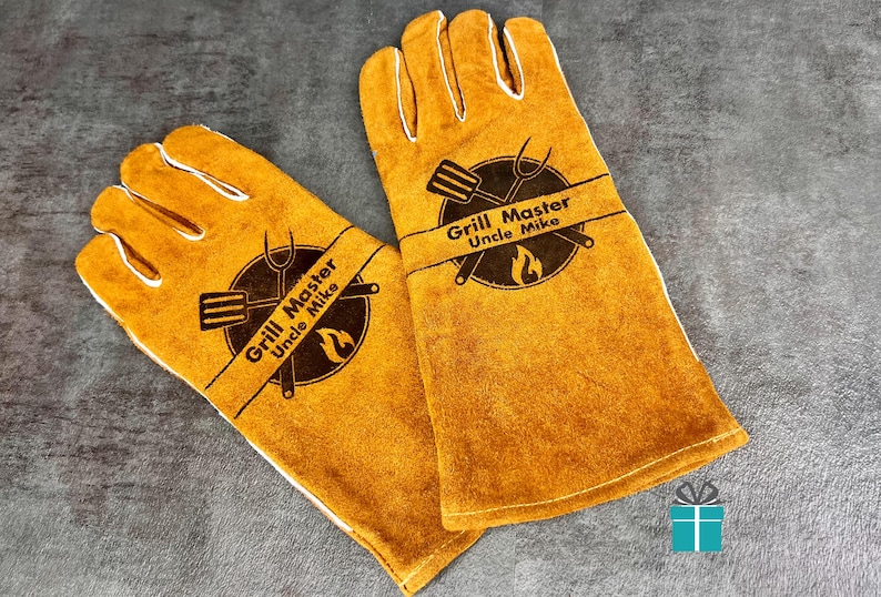 May include: A pair of yellow grilling gloves with white stitching. Each glove features a circular emblem with a spatula, fork, and flame, and the text "Grill Master Uncle Mike".