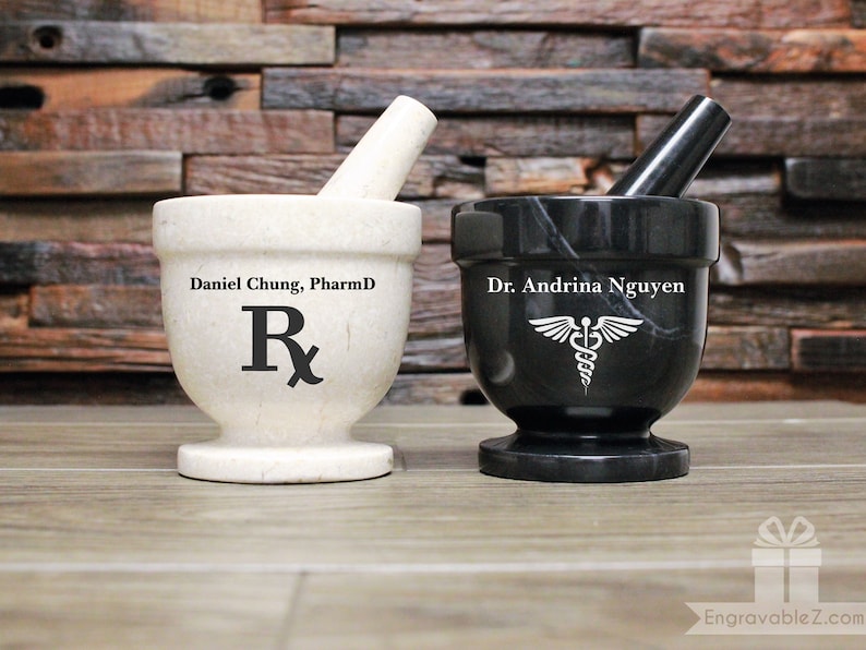 May include: Two personalised marble mortar and pestle sets. One is white with the text "Daniel Chung, PharmD" and an Rx symbol. The other is black with the text "Dr. Andrina Nguyen" and a caduceus symbol.