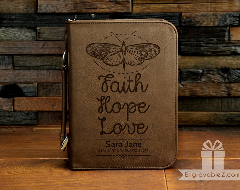 May include: Brown leather journal with a butterfly design and the words "Faith Hope Love" engraved on the front. The journal also has the text "Sara Jane Seminary Graduation 2017" engraved on the front.