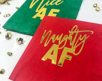 May include: Two Christmas themed paper napkins. One is red with gold foil lettering that says "Naughty AF". The other is green with gold foil lettering that says "Nice AF".