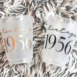 Frosted 16 ounce cups that read Vintage 1956 in black and gold ink.  70th Birthday Cups