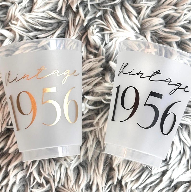 Frosted 16 ounce cups that read Vintage 1956 in black and gold ink.  70th Birthday Cups