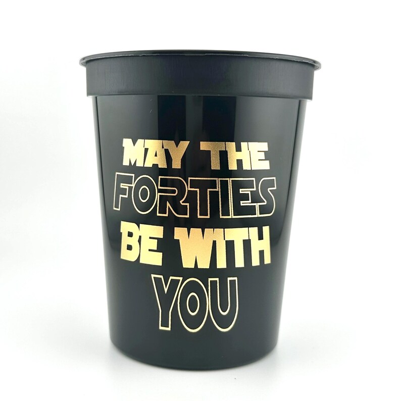 A black plastic stadium cup printed with gold text reading May the Forties be with you.