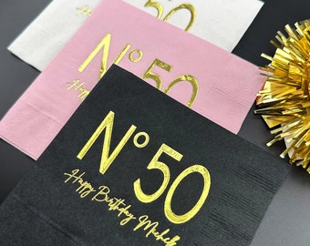 May include: Three square napkins with gold foil lettering. The napkins are white, pink, and black. The text on the napkins reads "N° 50" and "Happy Birthday Mike".