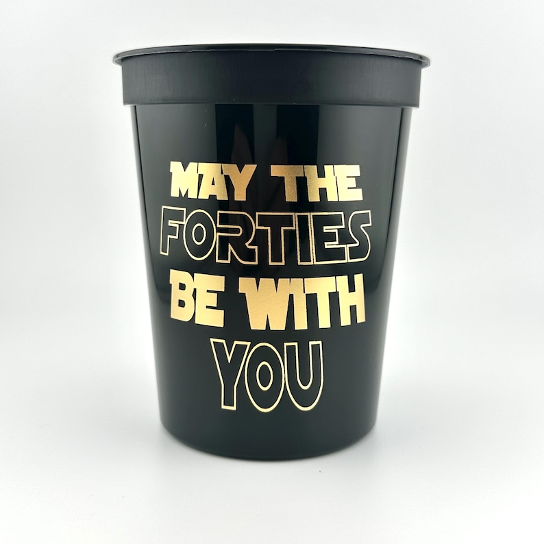 A black stadium cup with gold lettering that reads May the Forties be with you against a white background.