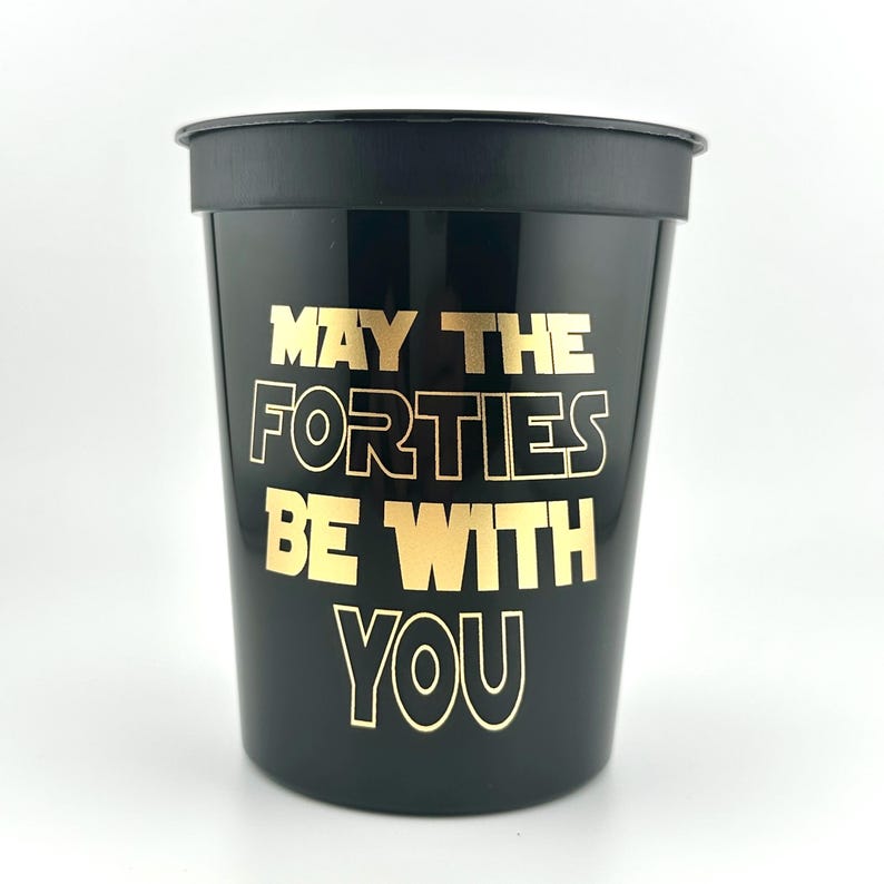 A black plastic stadium cup featuring gold printed text that reads May the Forties be with you.