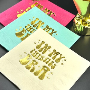 Pode incluir: Tr&ecirc;s guardanapos de papel com letras douradas. Os guardanapos s&atilde;o rosa, azul claro e branco. O texto nos guardanapos diz "In My Thirties Era".