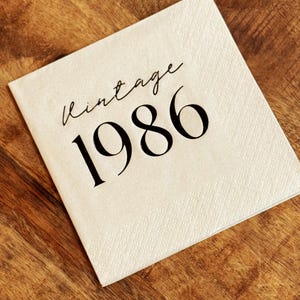 cream napkins with black foil that reads Vintage 1986