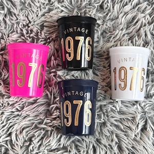 16 ounce stadium cups that read Vintage 1976 in gold metallic font.  the cups are black, navy, white and hot pink.  50th Birthday Cups