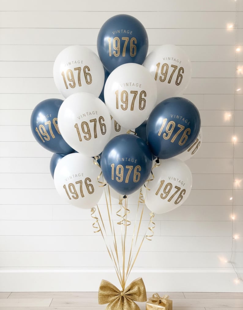 A balloon bouquet with navy and white latex balloons that read Vintage 1976 in a gold metallic font.  50th Birthday Balloon