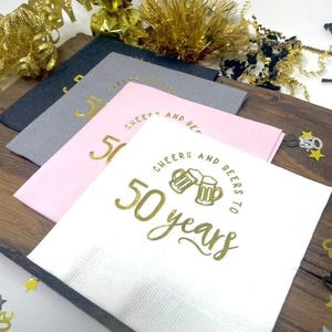 Cocktail napkins that read Cheers and beers to 50 years.  The napkins are stamped in a gold foil. 50th Anniversary or 50th Birthday Party Napkins