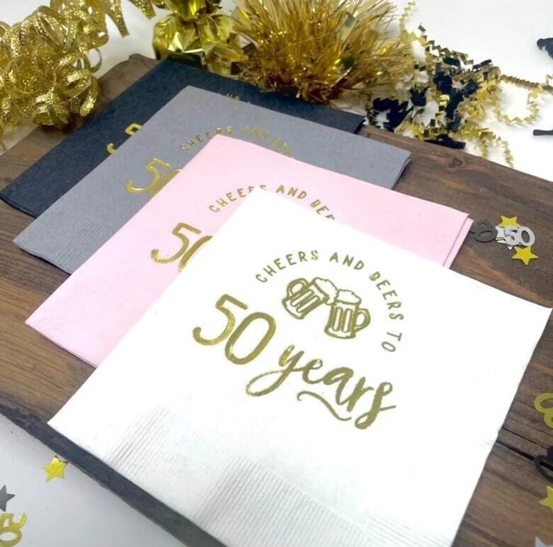 Cocktail napkins that read Cheers and beers to 50 years.  The napkins are stamped in a gold foil. 50th Anniversary or 50th Birthday Party Napkins