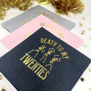 Paper cocktail  napkins with gold foil lettering that reads "Death to my twenties" with a graphic of three skeletons dancing. foil stamped 30th Birthday Napkin Decor