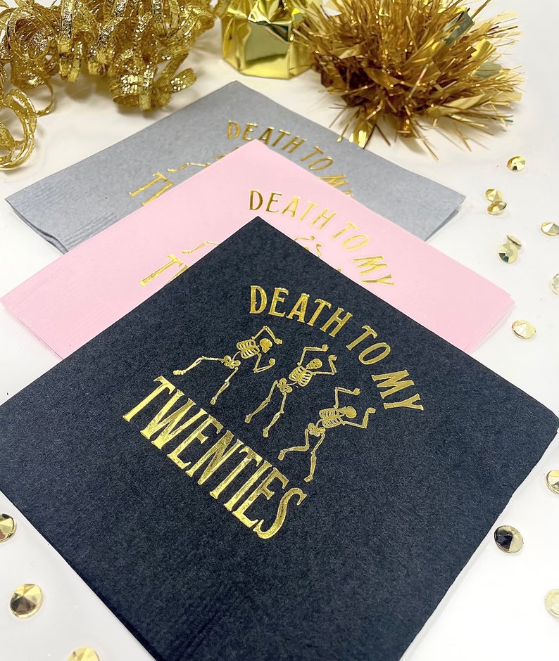 Paper cocktail  napkins with gold foil lettering that reads "Death to my twenties" with a graphic of three skeletons dancing. foil stamped 30th Birthday Napkin Decor
