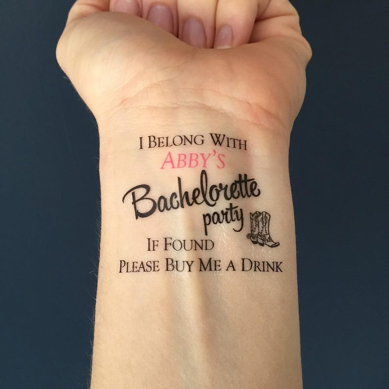 A temporary tattoo on a person's inner wrist reads "I BELONG WITH ABBY'S Bachelorette party IF FOUND PLEASE BUY ME A DRINK" with two cowboy boots.