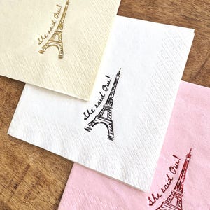Foil stamped cocktail napkin reading “She Said Oui” with Eiffel Tower graphic for Parisian bridal shower decor