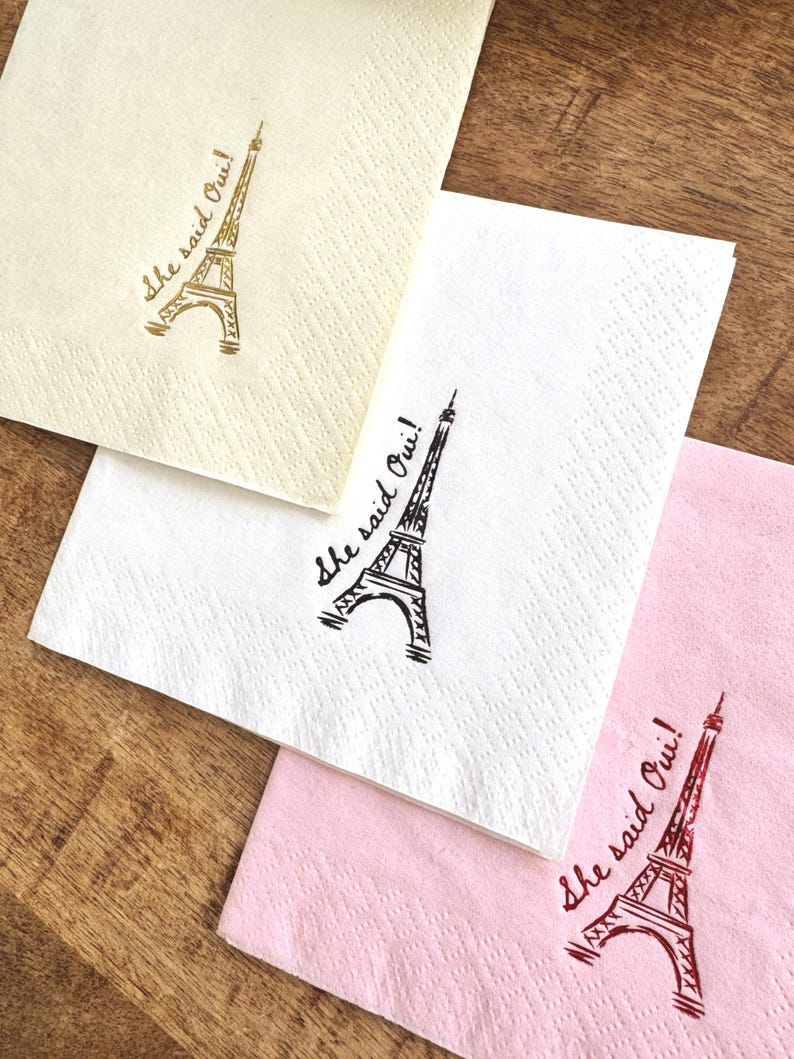 Foil stamped cocktail napkin reading “She Said Oui” with Eiffel Tower graphic for Parisian bridal shower decor